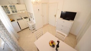 Ein gemütlicher Wohnbereich mit Küchenzeile, einem Essbereich mit Tisch für zwei Personen und einem Fernseher auf einem Schrank.