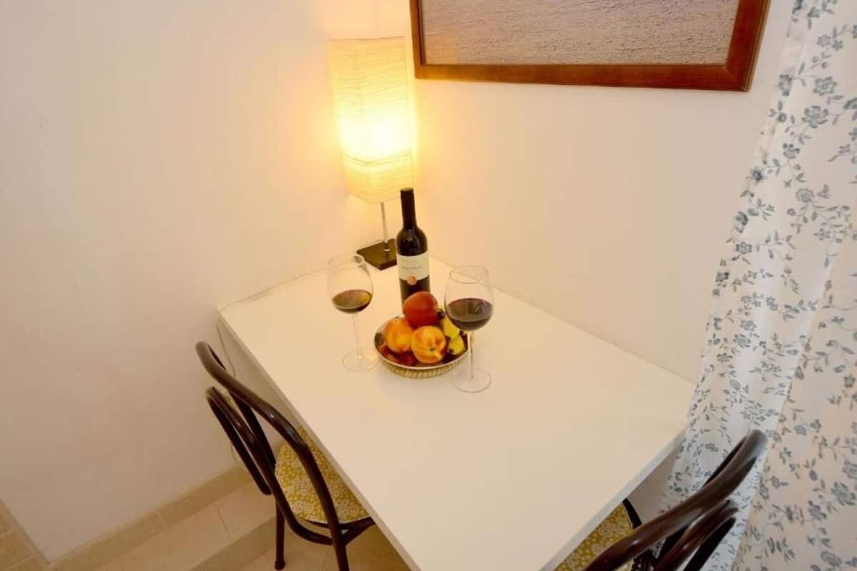 A dining table with two wine glasses, a bottle, and a fruit bowl.