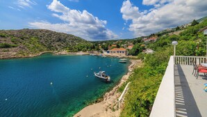 Uma vila costeira com águas azuis cristalinas, barcos e casas de telhados vermelhos.