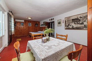 A dining area with a table set for four, wooden chairs, a lace tablecloth, and a vase with flowers. - House Ivanka (Karlobag)