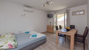 Un dormitori amb un llit, un escriptori amb cadires, una televisió i una finestra amb cortines.