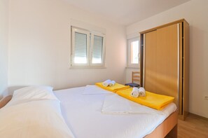 Ein Hotelzimmer mit einem Bett, einem Holzschrank, einem Fenster mit Rollläden und einem Sessel.