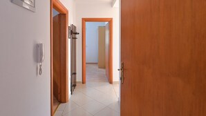 A hallway with a wooden door, a telephone, and a framed certificate on the wall. - Apartments Ilija (Novalja)