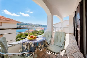 Un balcone con tavolo, sedie e una ciotola di frutta.