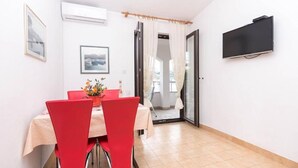 A dining area with a table, chairs, and a TV on the wall. - Apartments Marko (Pag)