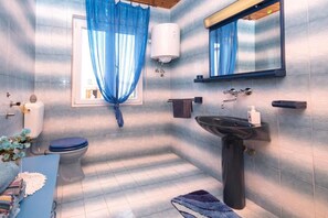 A bathroom with a toilet, sink, and blue shower curtain. - Apartments Marko (Pag)