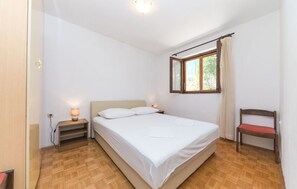 A bedroom with a single bed, a nightstand with a lamp, a chair, and a window with curtains. - House Jelka (Okrug)