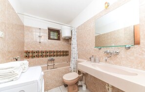 A modern bathroom with a bathtub, toilet, and sink. - House Jelka (Okrug)