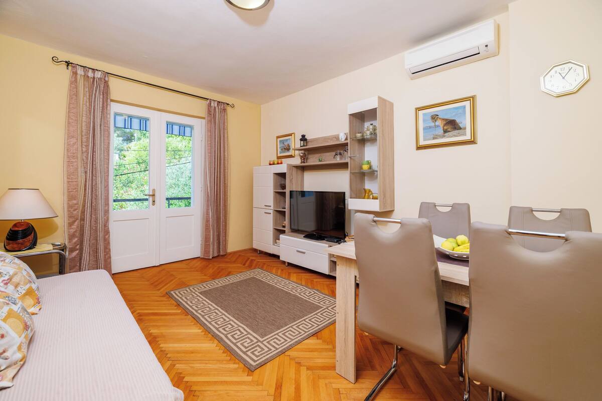 A compact room with a bed, a desk with a computer, a chair, a TV, and a small dining area.