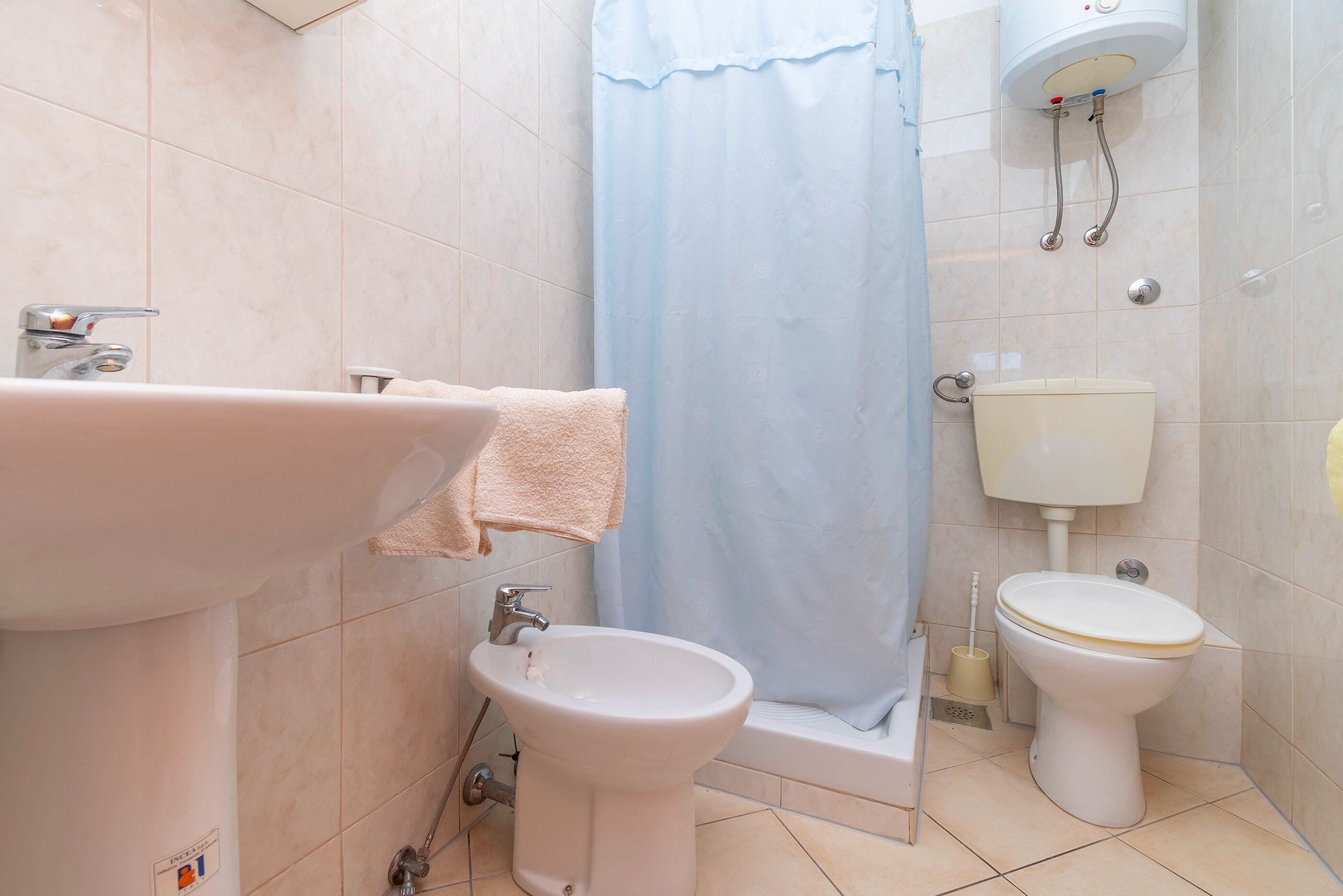 Une salle de bain équipée d’un lavabo, d’un bidet, de toilettes et d’un rideau de douche.
