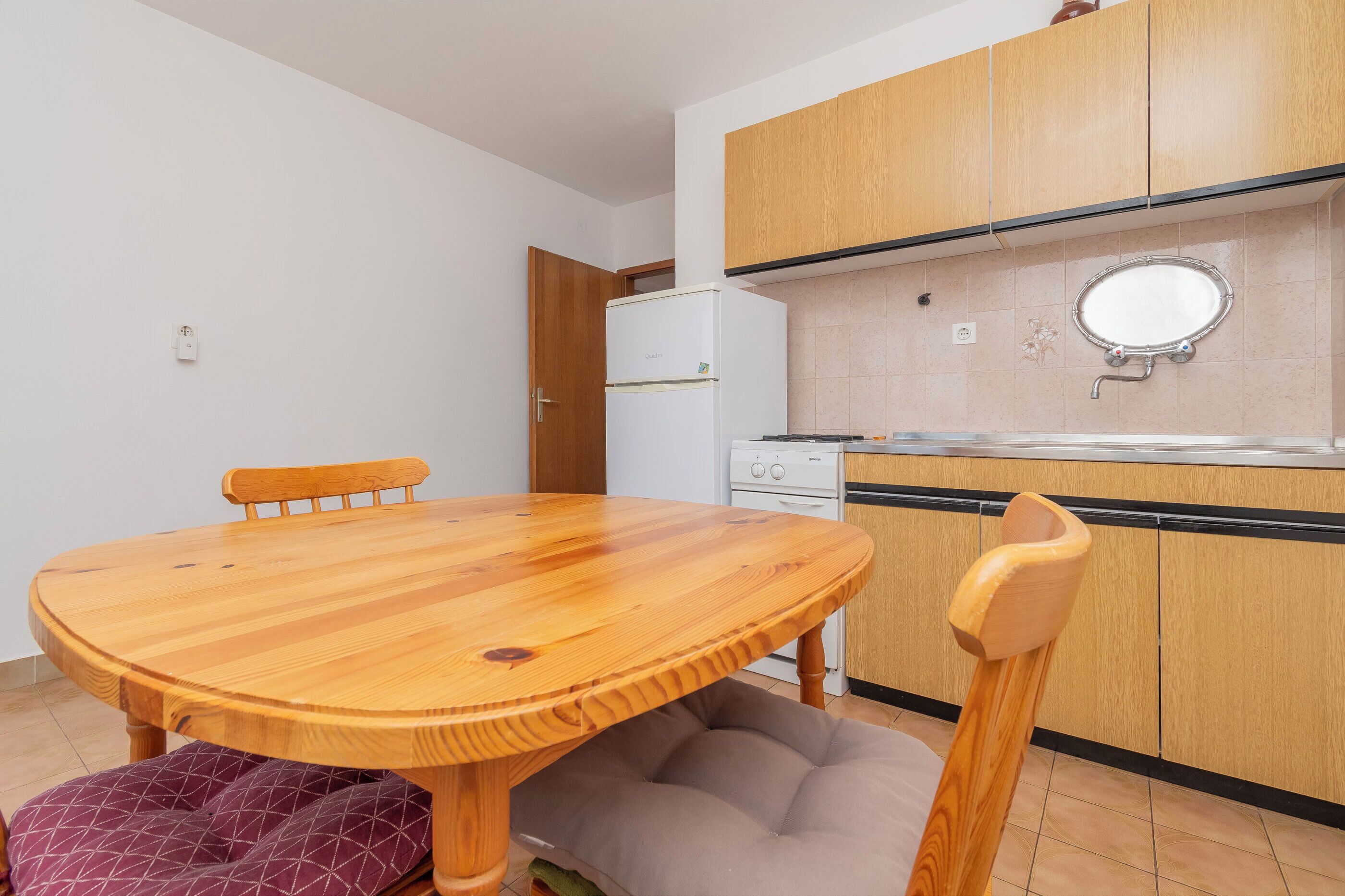 A compact kitchen with wooden cabinets, a white refrigerator, and a sink with a mirror above it.