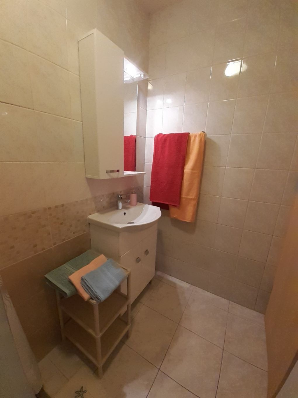 A small bathroom with a sink, mirror, and two towels hanging on the wall.