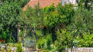 Ein Haus mit rotem Ziegeldach, umgeben von üppiger Vegetation und einer Steinmauer.
