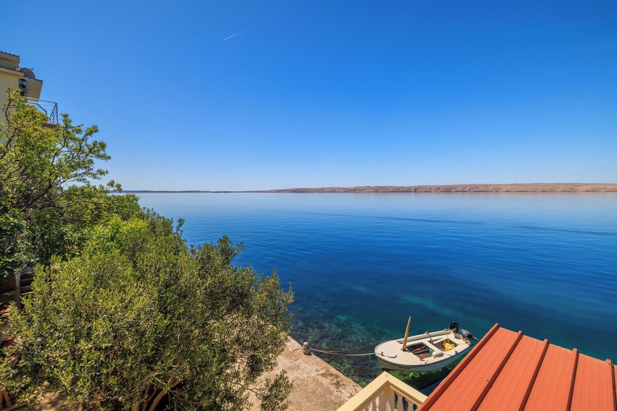 Blick auf die Küste mit einem Boot, das in der Nähe eines Gebäudes mit rotem Dach liegt.