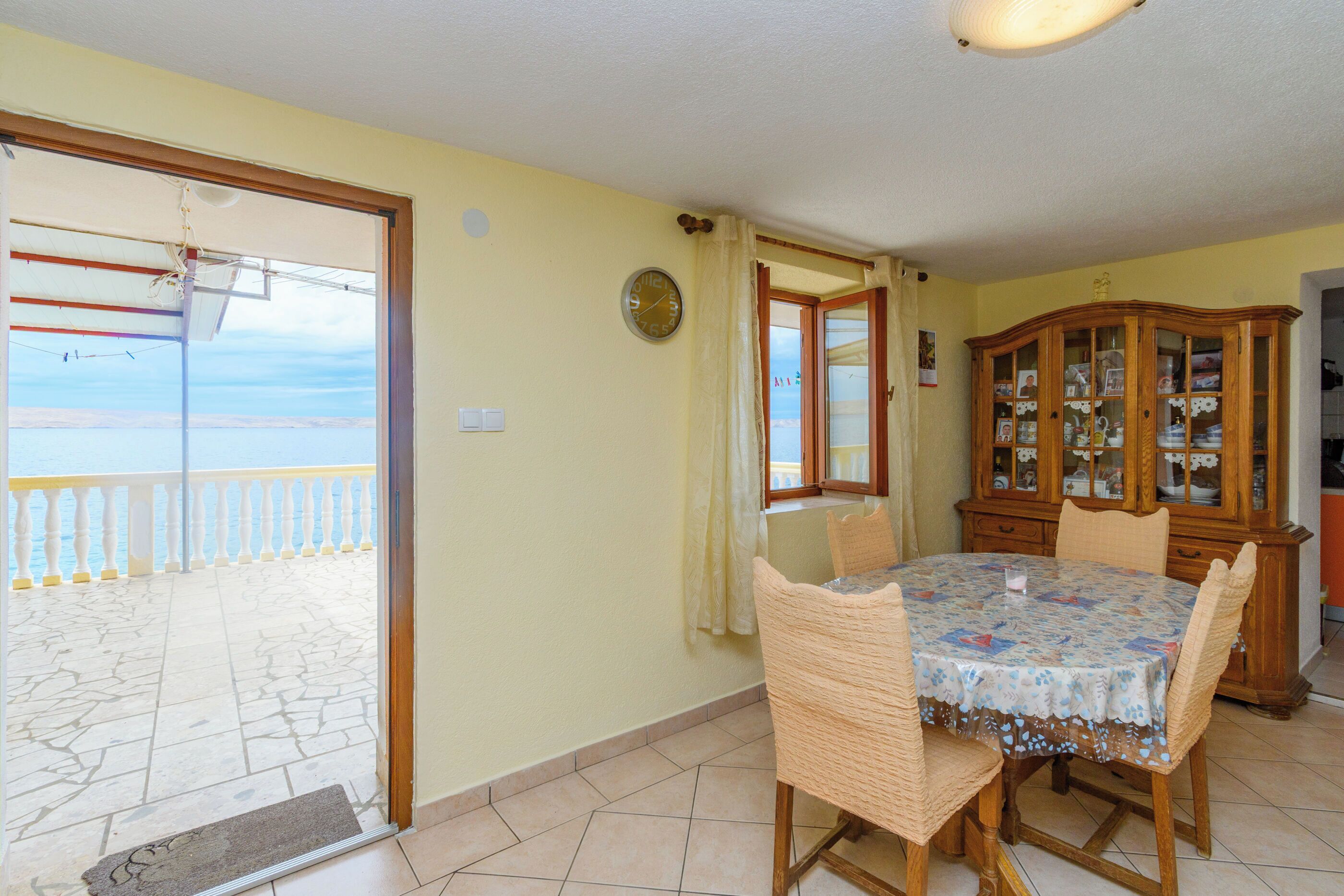 Un comedor con una mesa y sillas, un armario de madera y vistas al balcón exterior a través de un ventanal.