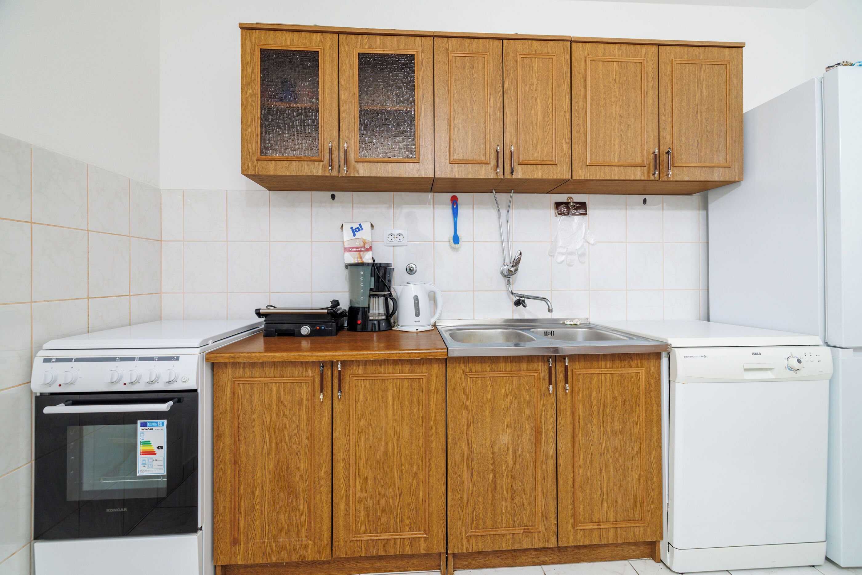 A kitchen with wooden cabinets, a stove, a dishwasher, and a coffee maker.