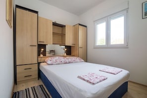 Une chambre à coucher comprenant un lit, une table de chevet, un bureau avec une lampe et des armoires encastrées en bois.