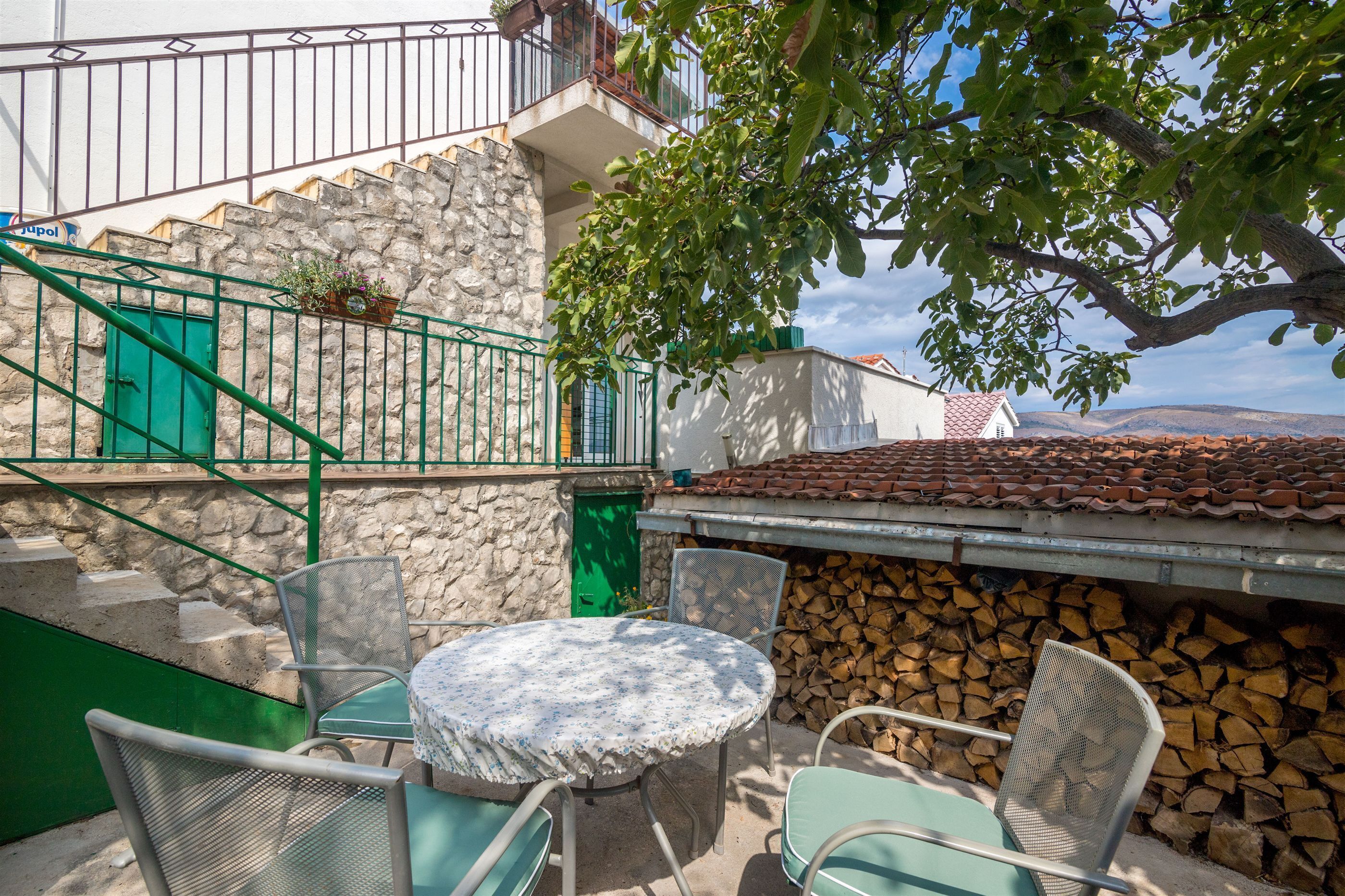 A patio with a round table and chairs, a stone staircase, and a view of the countryside.