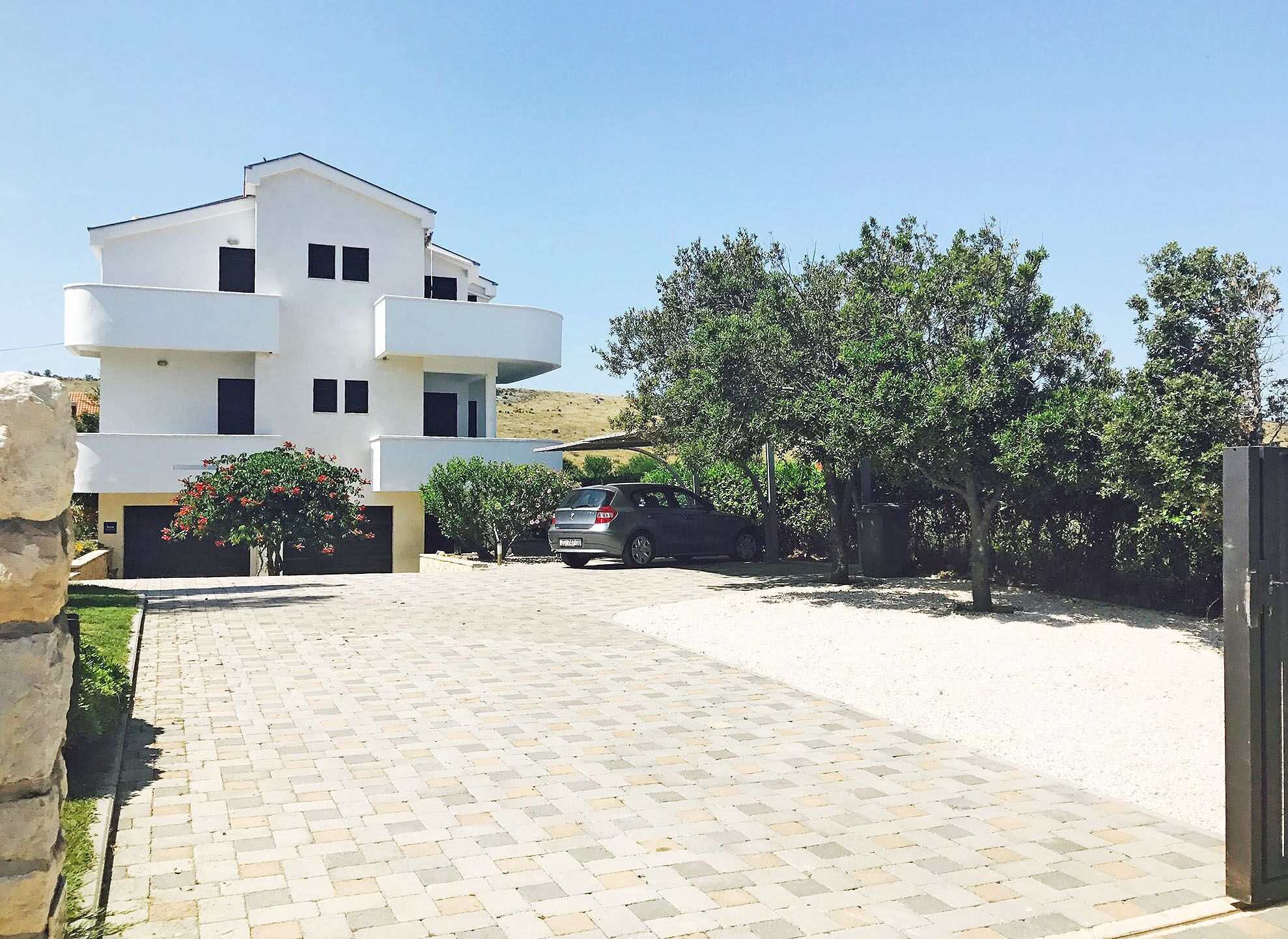 A modern two-story building with a paved driveway and a parked car.