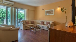 A living room with a beige sofa, a glass coffee table, and a wooden side table. - Apartments Blue Skies (Razanac)