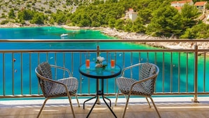 A balcony with two checkered chairs and a small round table, overlooking a turquoise sea and a hillside with buildings. - House Silva (Rogoznica)