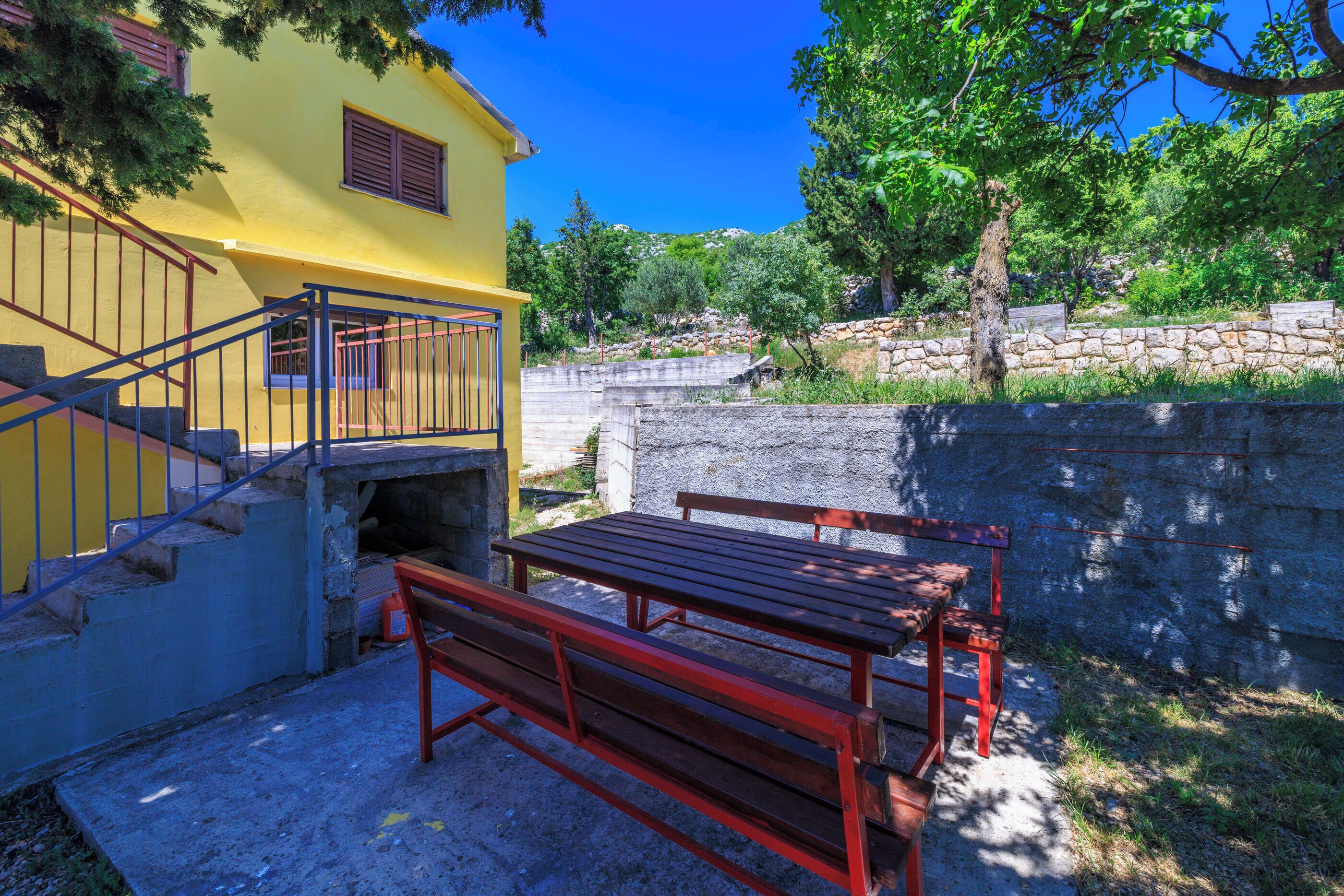 A yellow building with a staircase and a wooden bench.