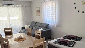 A modern living space with a dining area, sofa, and a wall clock. - Apartment Kety (Novalja)