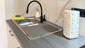 A kitchen with a modern sink, a faucet, a sponge, a soap dispenser, and a patterned paper towel holder. - Apartment Kety (Novalja)