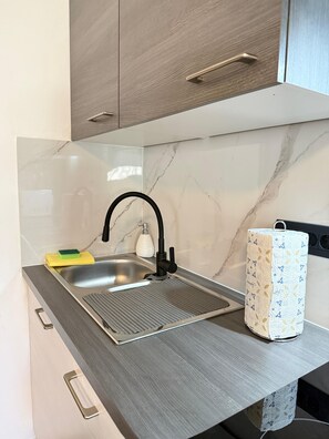 A kitchen with a modern sink, a faucet, a sponge, a soap dispenser, and a patterned paper towel holder. - Apartment Kety (Novalja)