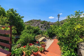 Eine Gartenpatio mit einer Holzbank, Topfpflanzen und einem Steinweg.