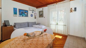 A bedroom with a bed, a desk, and a table with a lace tablecloth. - Apartment Ivan (Karlobag)