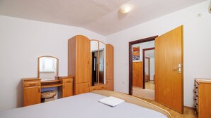 A bedroom with a bed, wooden wardrobe, and a mirror. - Apartments Jase (Karlobag)