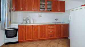 A kitchen with wooden cabinets, a stove, and a sink. - Apartments Jase (Karlobag)