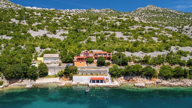 A coastal property with a large house, a smaller building, and a dock extending into clear turquoise waters. - Apartments Jase (Karlobag)