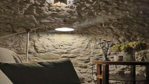 Ein gemütliches Zimmer mit einer Steinwand, einem runden Tisch mit einer Vase und einer Lampe.