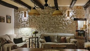 Ein rustikales Wohnzimmer mit freiliegenden Steinwänden, einem Holzessttisch und einem Sofa.