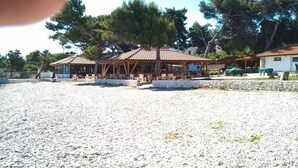 Un edificio sul lungomare con posti a sedere all'aperto e un muro in pietra.