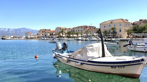 Una marina con imbarcazioni ormeggiate, acqua limpida e edifici sullo sfondo.