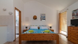 Een slaapkamer met een houten bed, twee nachtkastjes, een televisie en een schilderij aan de muur.
