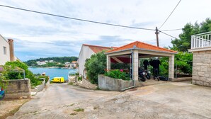 A coastal property with a covered patio, a yellow car, and a view of the sea. - Apartments Dado (Lumbarda)