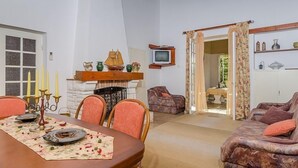 Un coin repas avec une table en bois dressée pour quatre personnes, une cheminée et un téléviseur fixé au mur.