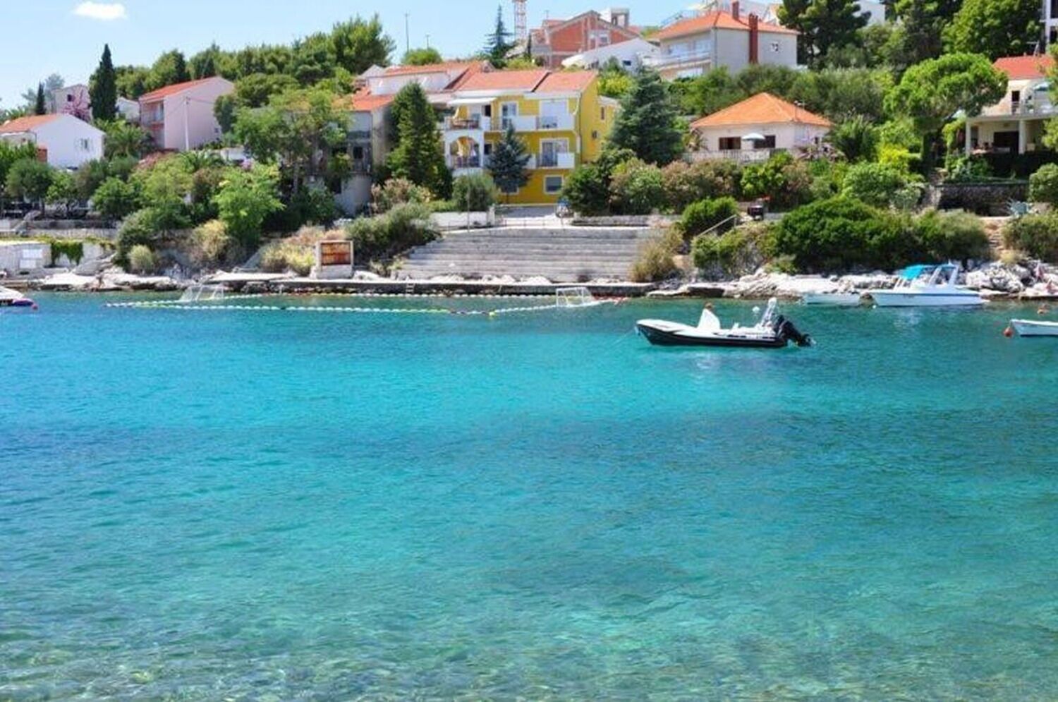 Un pueblo costero con aguas turquesas cristalinas, barcos y edificios coloridos.