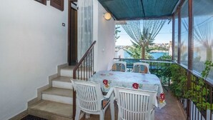 Ein überdachter Außenbereich mit Tisch und Stühlen, einer Treppe und Blick auf ein Gewässer.
