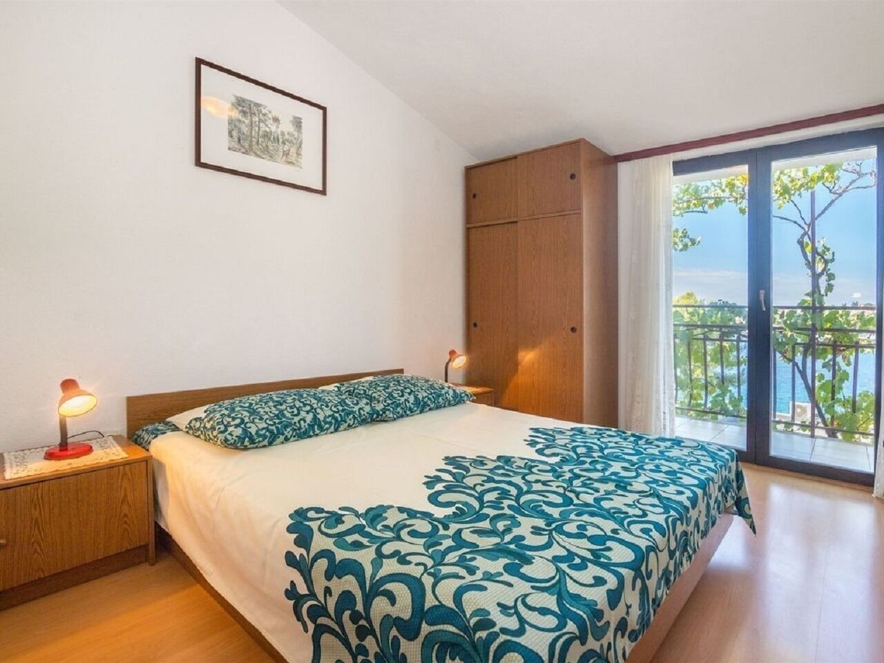 Una camera da letto con un letto, comodini, un armadio in legno e un balcone con vista.