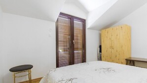 A bedroom with a bed, a wooden wardrobe, a small table, and a bench. - Apartments Milans (Rogoznica)