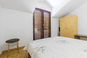 Una camera da letto con un letto, un armadio in legno, un tavolino e una panca.