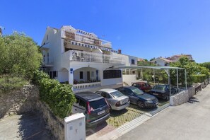 Un edificio a due piani con un'area parcheggio coperta e un muro in pietra.