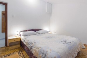 A bedroom with a bed, nightstand, and a wall-mounted light fixture. - Apartments Milans (Rogoznica)