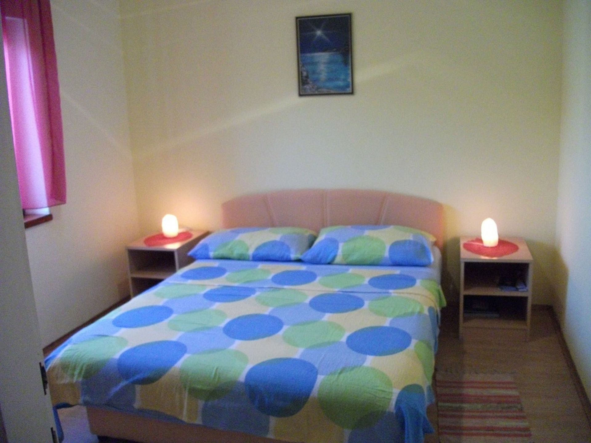 Ein kleines Schlafzimmer mit einem Bett, zwei Nachttischen und einem Beistelltisch mit einer Lampe.