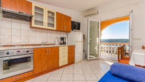A modern kitchen with wooden cabinets, a Koncar stove, and a balcony with a view. - Apartments Adriatic (Razanac)